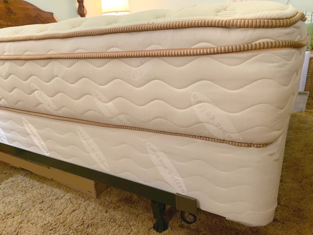 Saatva mattress on box springs on bed frame on carpet in bedroom