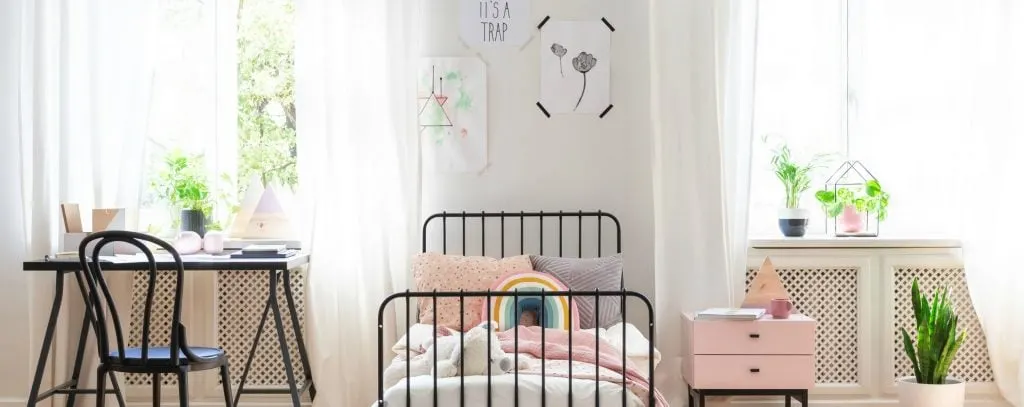 teenagers bedroom with bright airy windows, pink accents lots of green plants and black metal furniture