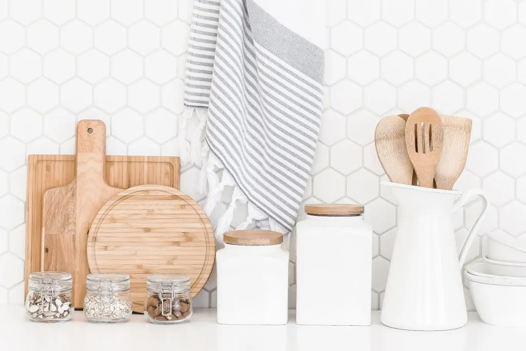 wooden cutting boards white storage containers and glass mason jars against white backsplash in kitchen