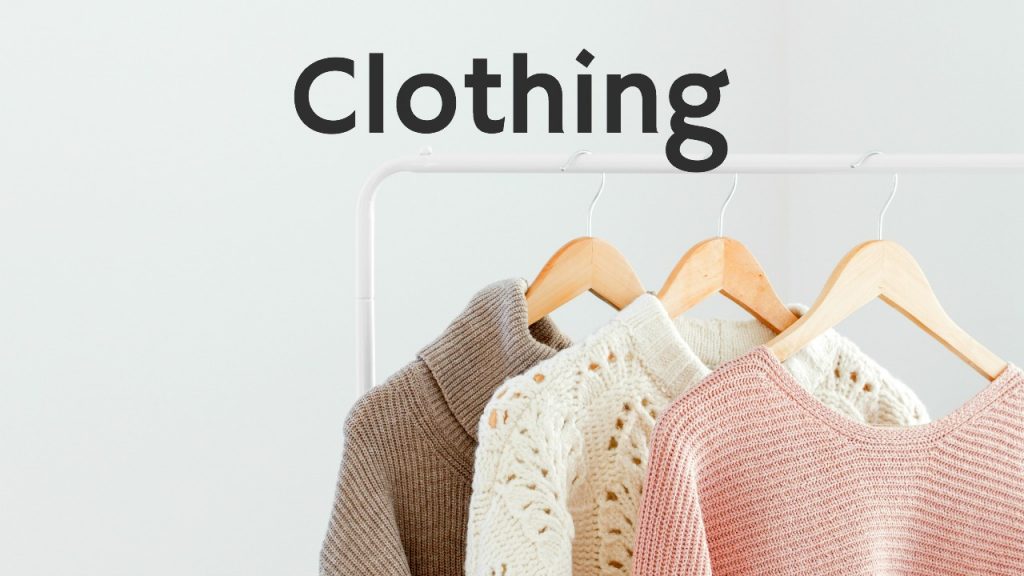 sweaters hanging on hangers on clothing rack against white wall