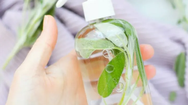 A DIY sage spray being held by a hand.