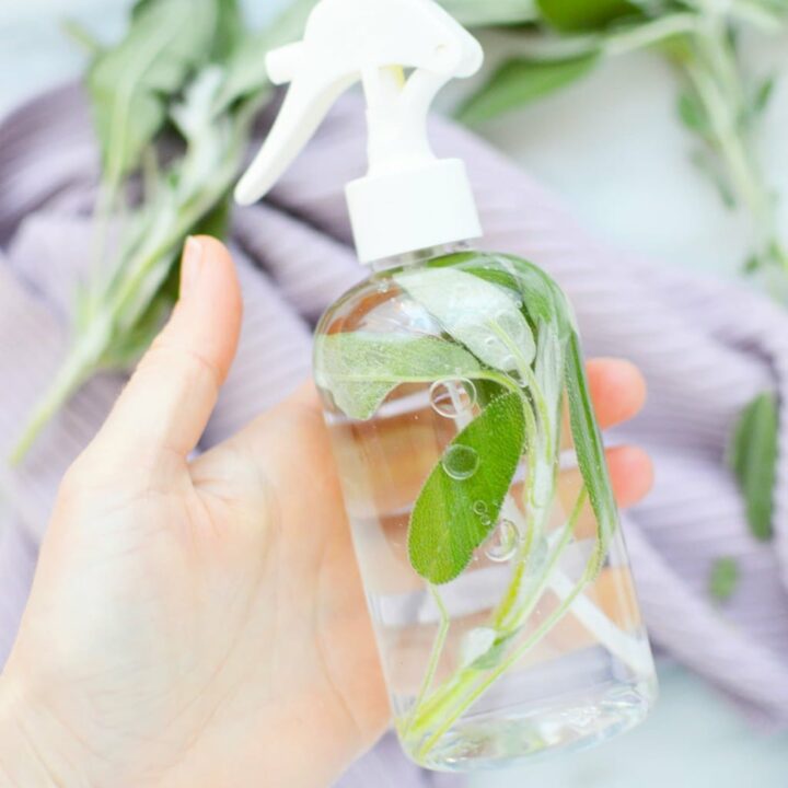 A DIY sage spray being held by a hand.