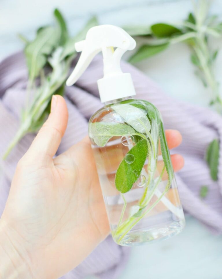 A DIY sage spray being held by a hand.