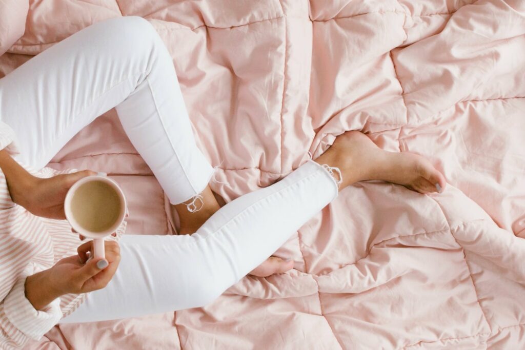 woman wearing white jeans sitting on pink cozy comforter