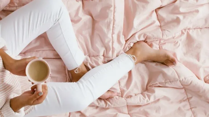 woman wearing white jeans sitting on pink cozy comforter