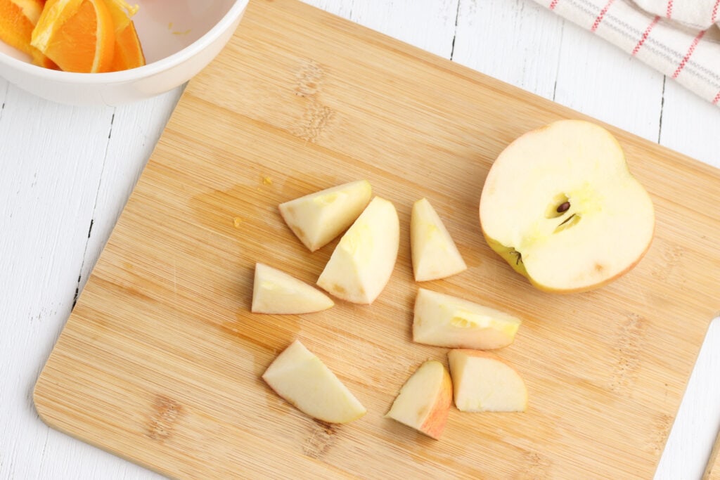 apple on wooden cutting board cut into chunks
