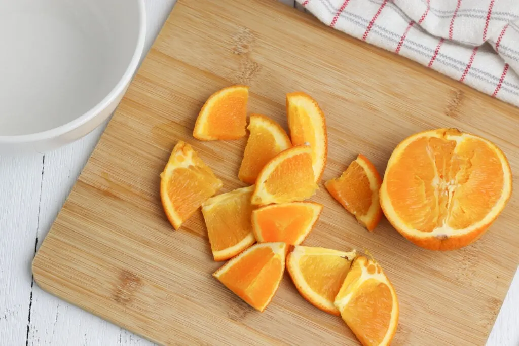 orange cut into chunks on wooden cutting board