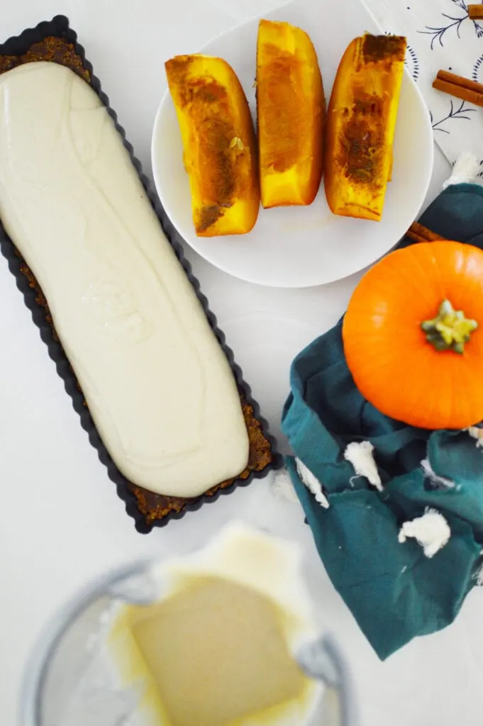 graham cracker crust in tart pan with pumpkin slices on a white plate