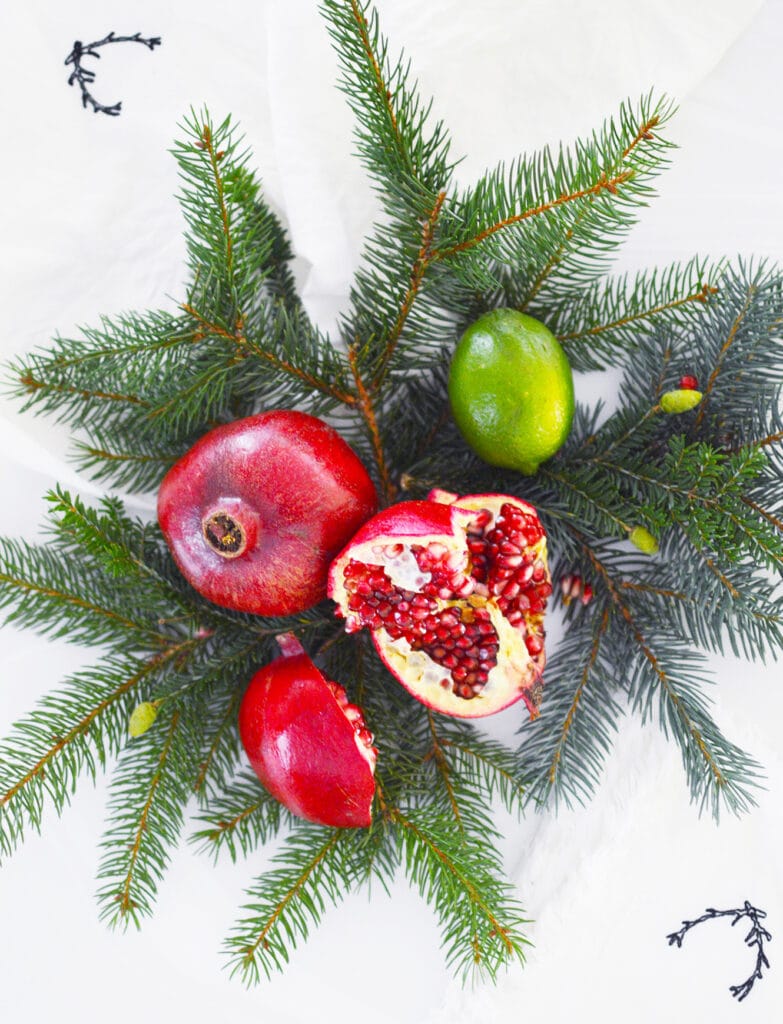 pomegranates on top of pine needles on white background