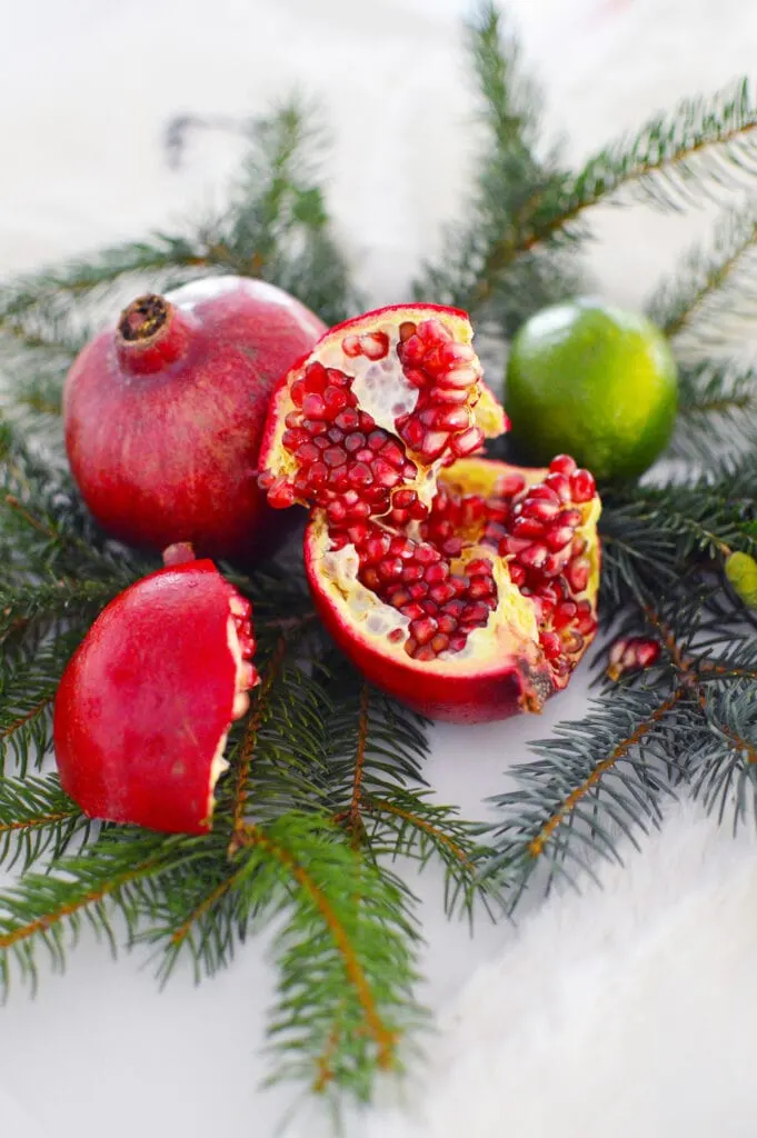 pomegranates and limes on fresh pine needles