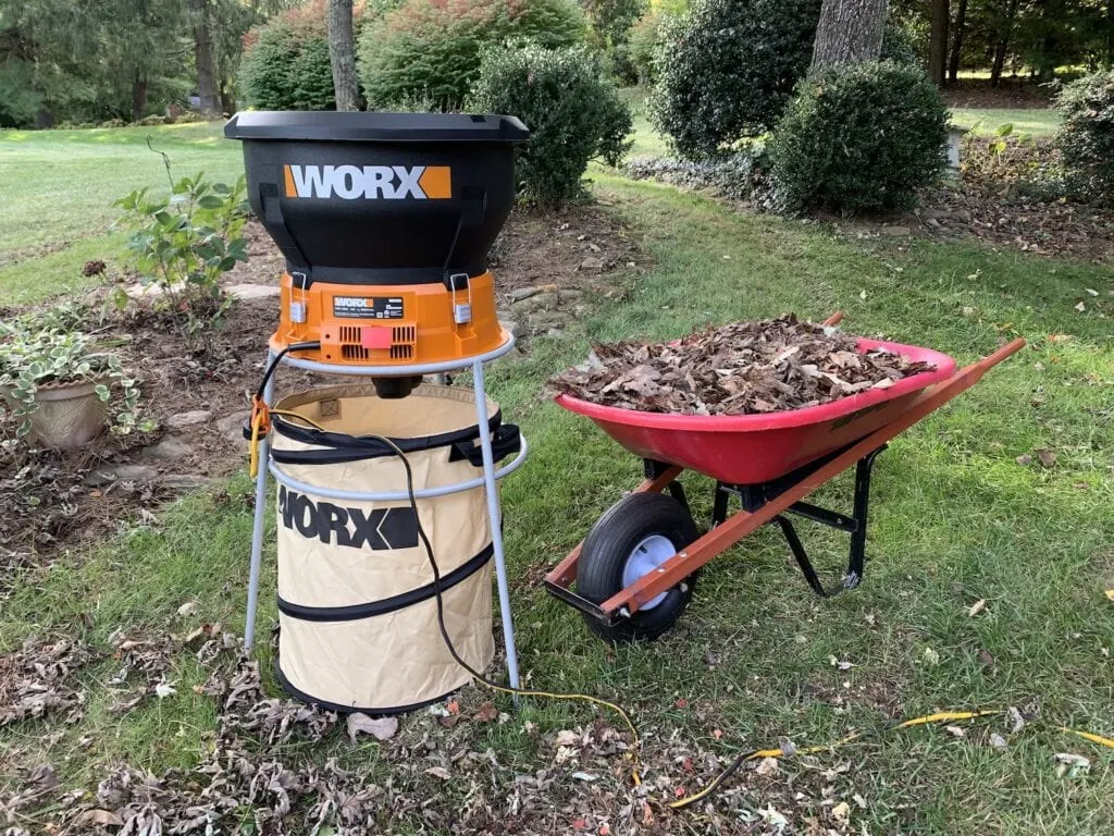 worx leaf shredder with red wheelbarrow filled with dead leaves for mulching