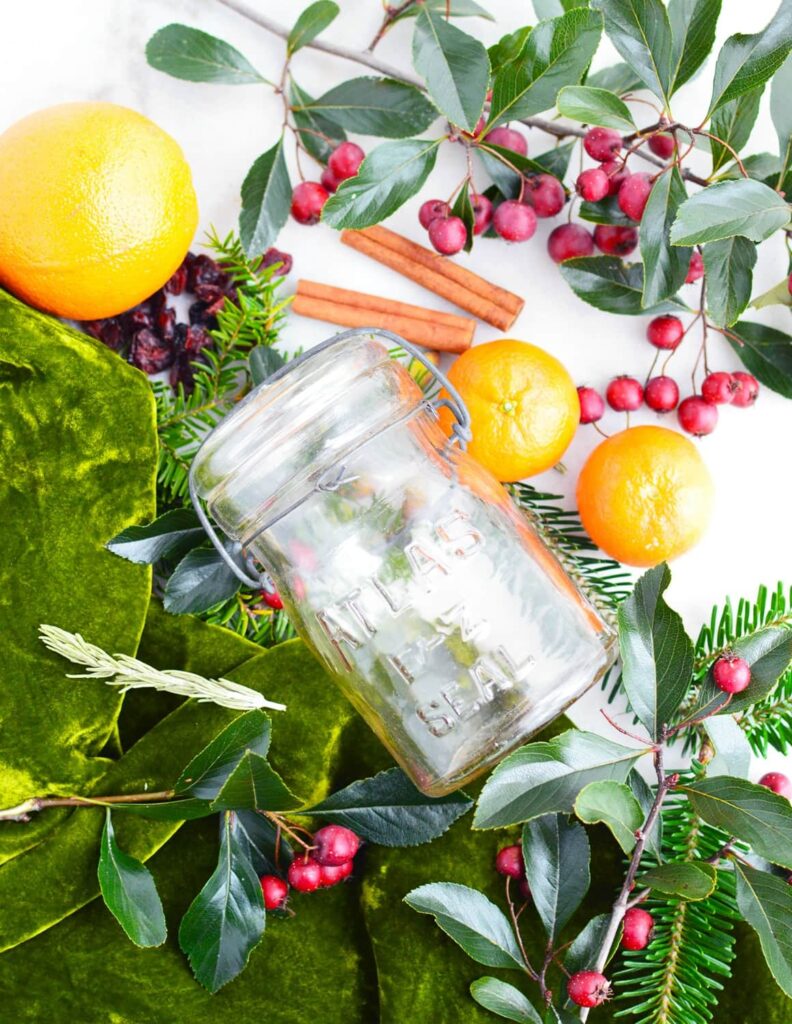 glass jar on crab apple oranges and greenery