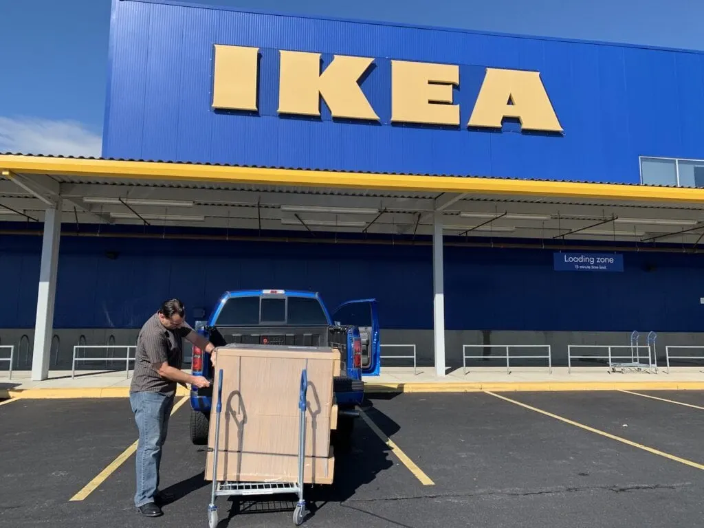 man loading IKEA furniture boxes into truck outside of IKEA store