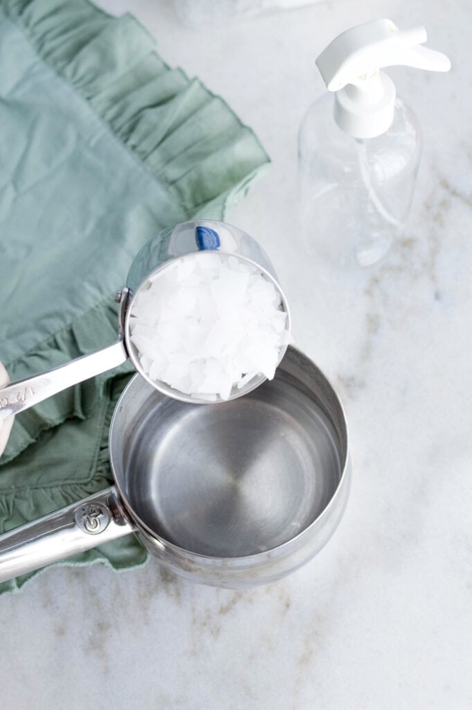 measuring cup of magnesium flakes over steel pot on white background magnesium topical spray recipe