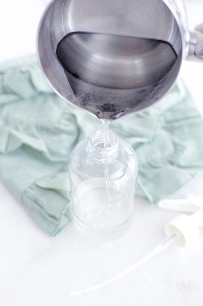 pouring magnesium topical spray into glass bottle