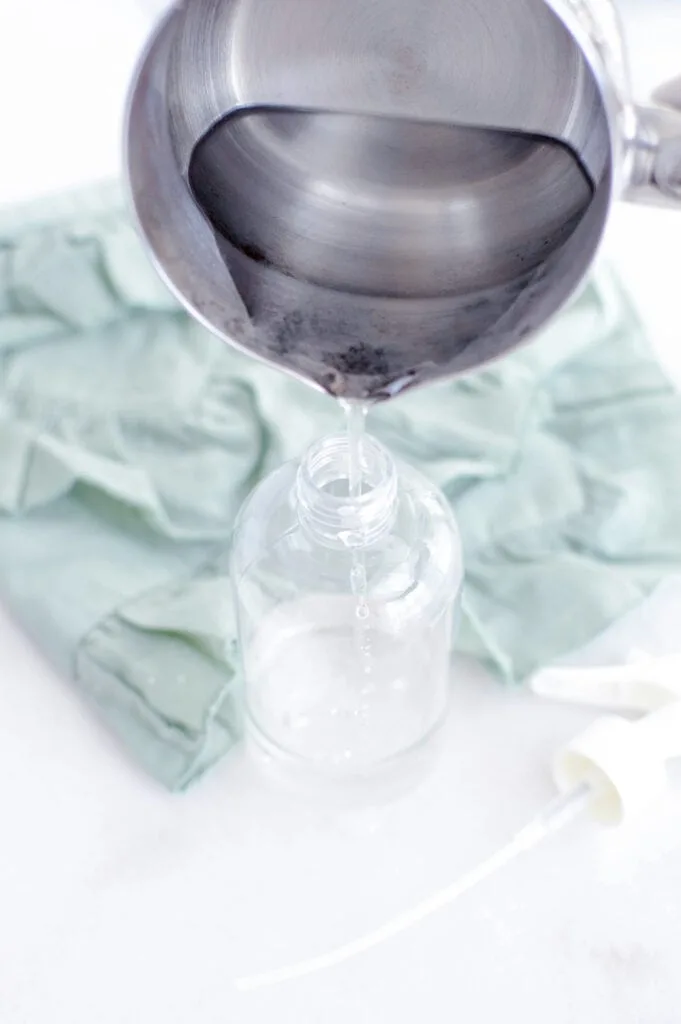 pouring magnesium topical spray into glass bottle