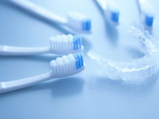 toothbrushes next to retainer on blue background
