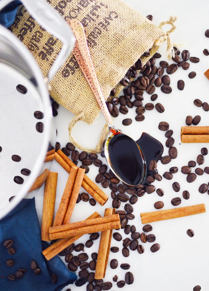 coffee beans cinnamon sticks and molasses on white background