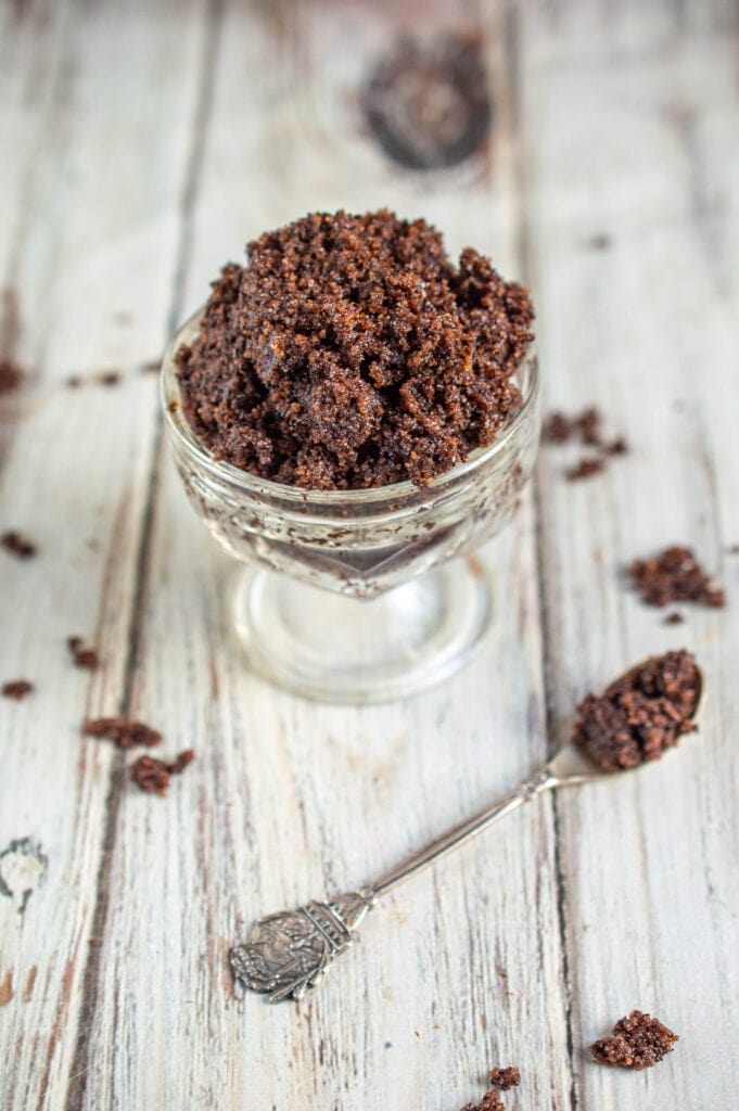 coffee sugar scrub in glass bowl with silver spoon on wooden white table