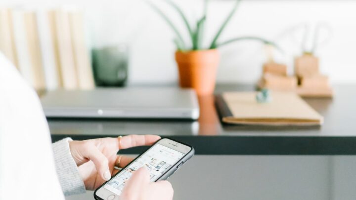 woman scrolling through social media on phone in home office