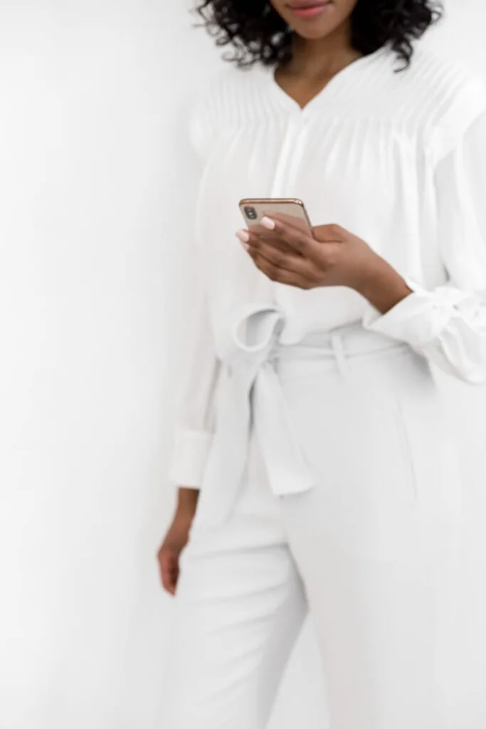 woman in white scrolling on phone on social media