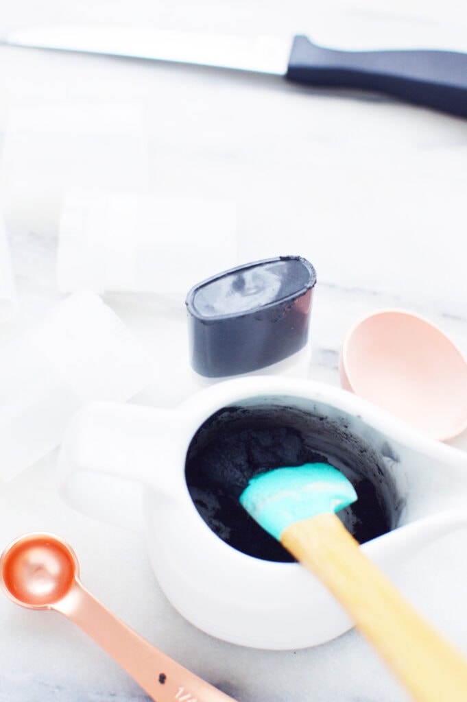 charcoal powder in white bowl with spatula on marble surface