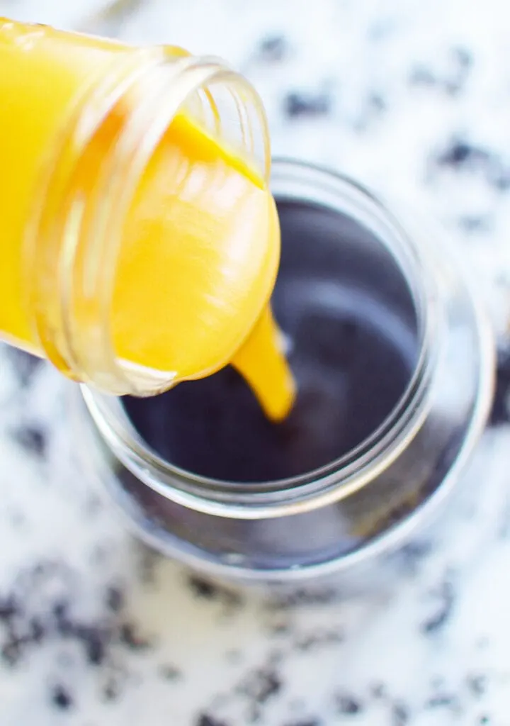 honey poured into elderberry syrup in glass jar