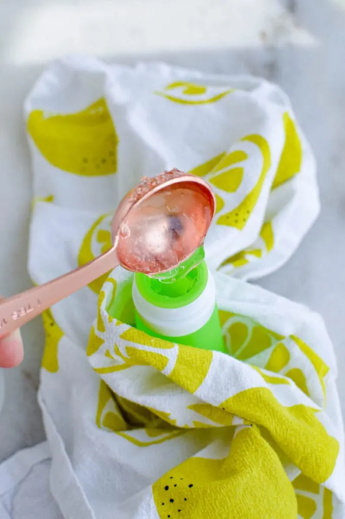 pouring aloe vera gel into green tube for hand sanitizer recipe