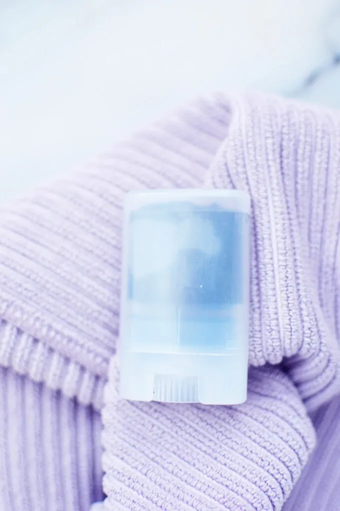 plastic container with black paste inside against purple towel