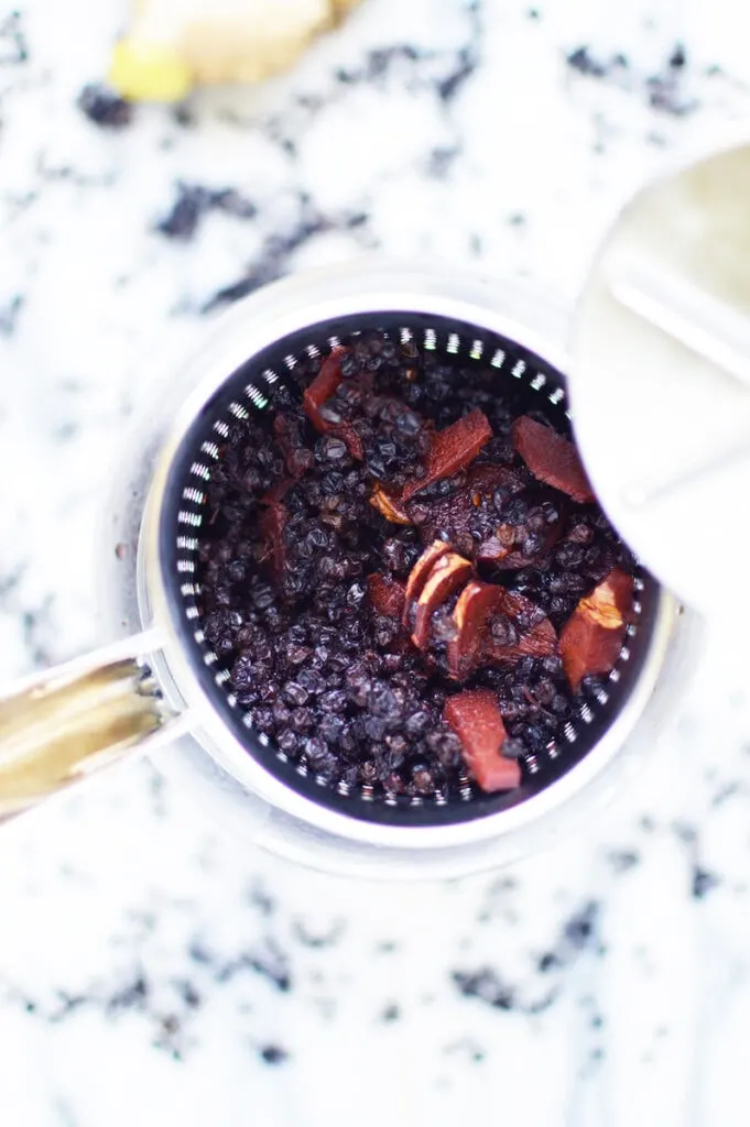 used elderberries in strainer on marble background