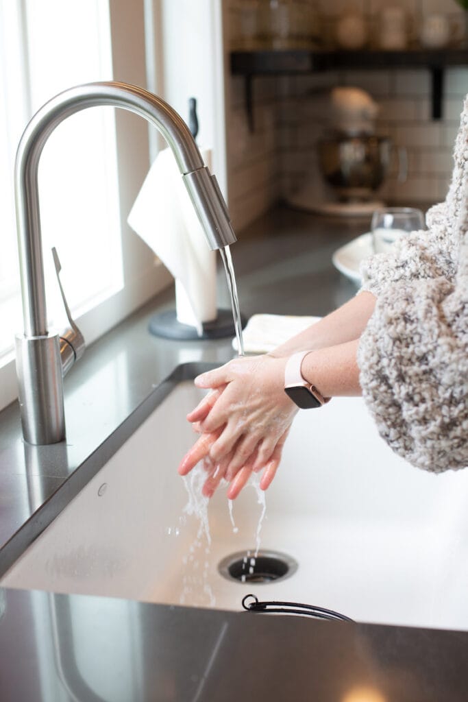 woman washing hands at kitchen sink