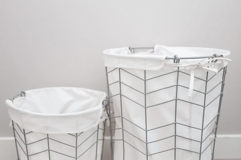 metal laundry hampers with white cloth liners against gray wall