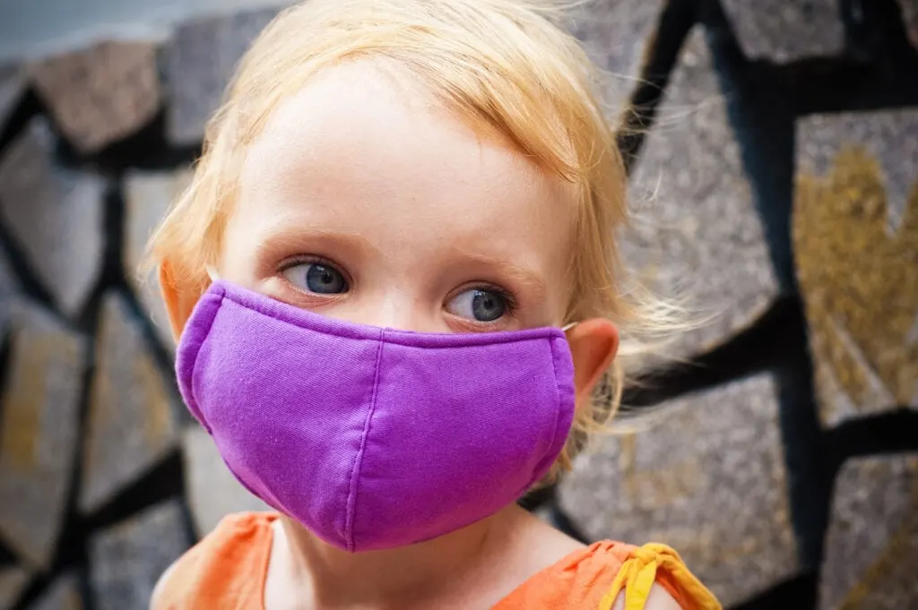 young girl wearing purple cloth face mask
