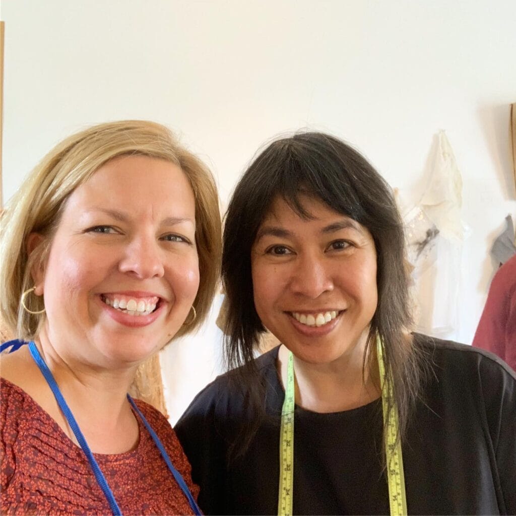 two women smiling wearing tape measures around necks