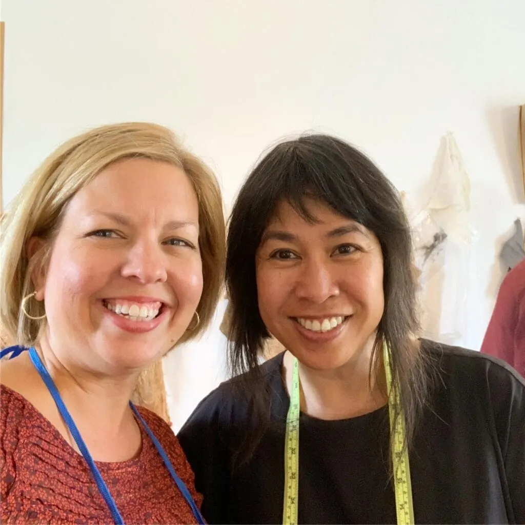 two women smiling wearing tape measures around necks