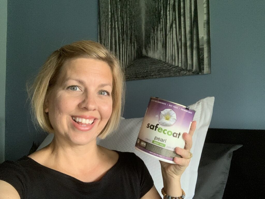 woman holding a small can of paint in a bedroom