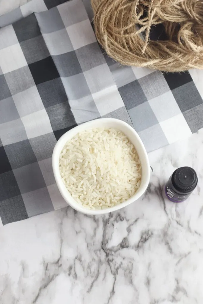 bowl of white rice on grey and white plaid fabric with bottle of essential oil nearby