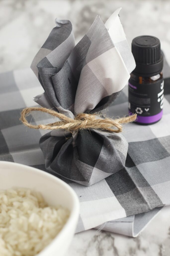 dresser sachet made from grey and white checked fabric next to bowl of rice and bottle of essential oils