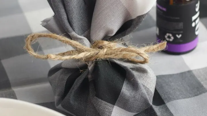 dresser sachet made from grey and white checked fabric next to bowl of rice and bottle of essential oils