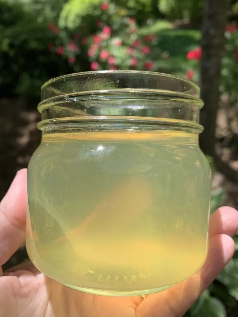 hand holding small glass jar filled with yellow gelatin air freshener