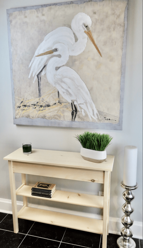 solid wood table with a large painting on wall above