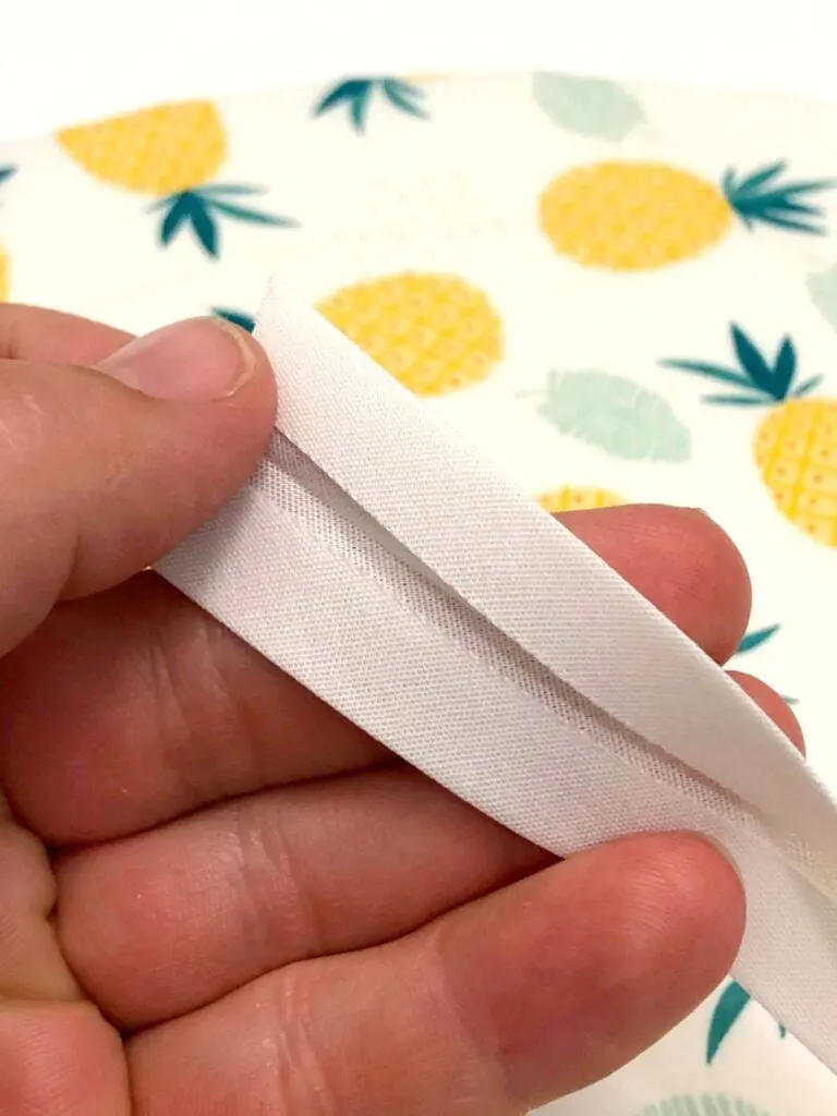 white bias tape unfolded in woman's hand for sewing project
