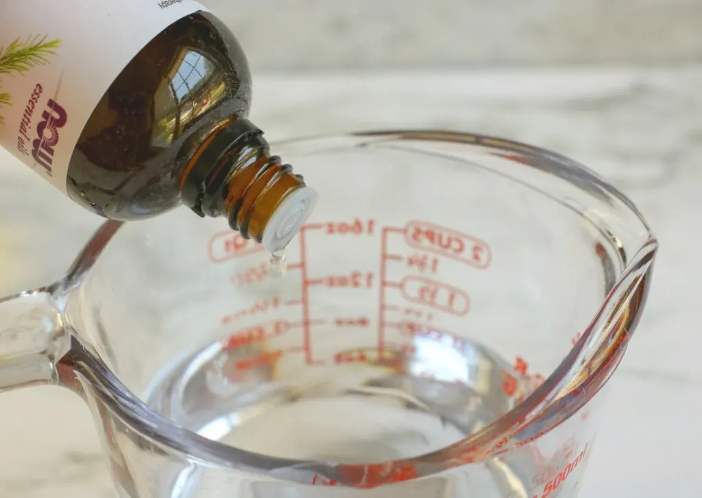 dropping essential oils into measuring cup of water