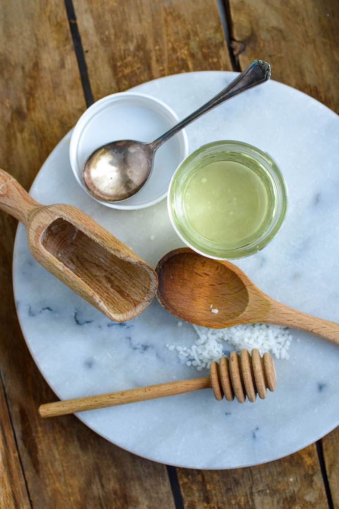 wooden spoons, jar of coconut oil and beeswax pellets on marble platter 