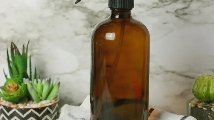 brown spray bottle on top of cleaning rags