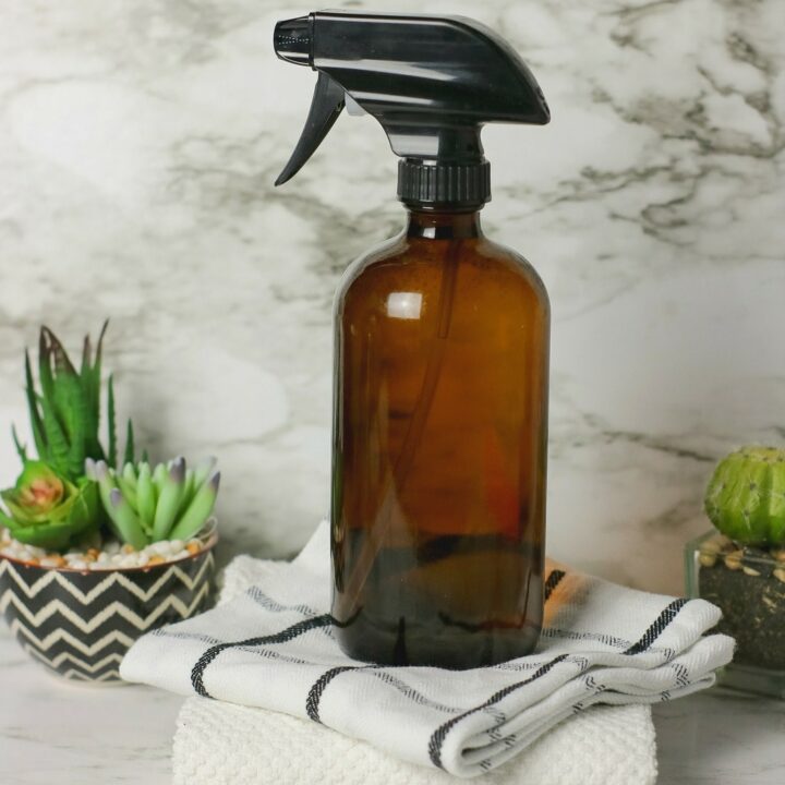 brown spray bottle on top of cleaning rags