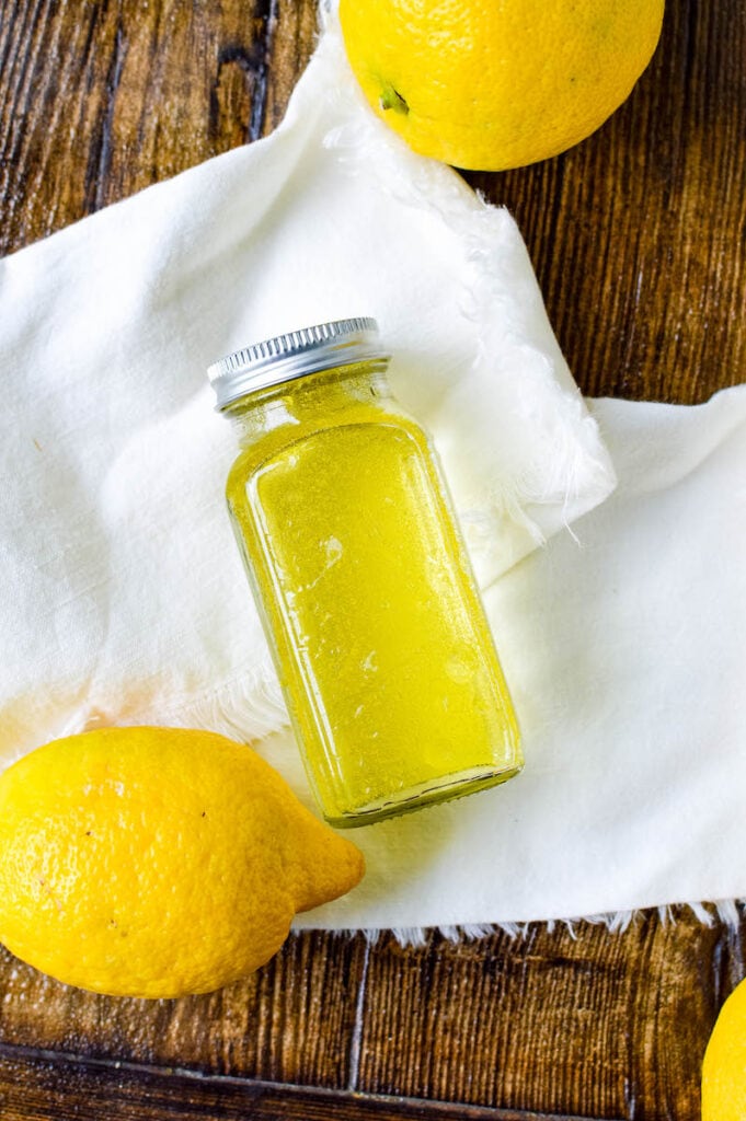 glass bottle full of olive oil vinegar and lemon juice lying on white cloth
