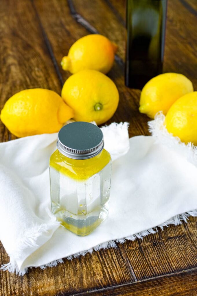 glass bottle filled with vinegar and olive oil sitting on white rag