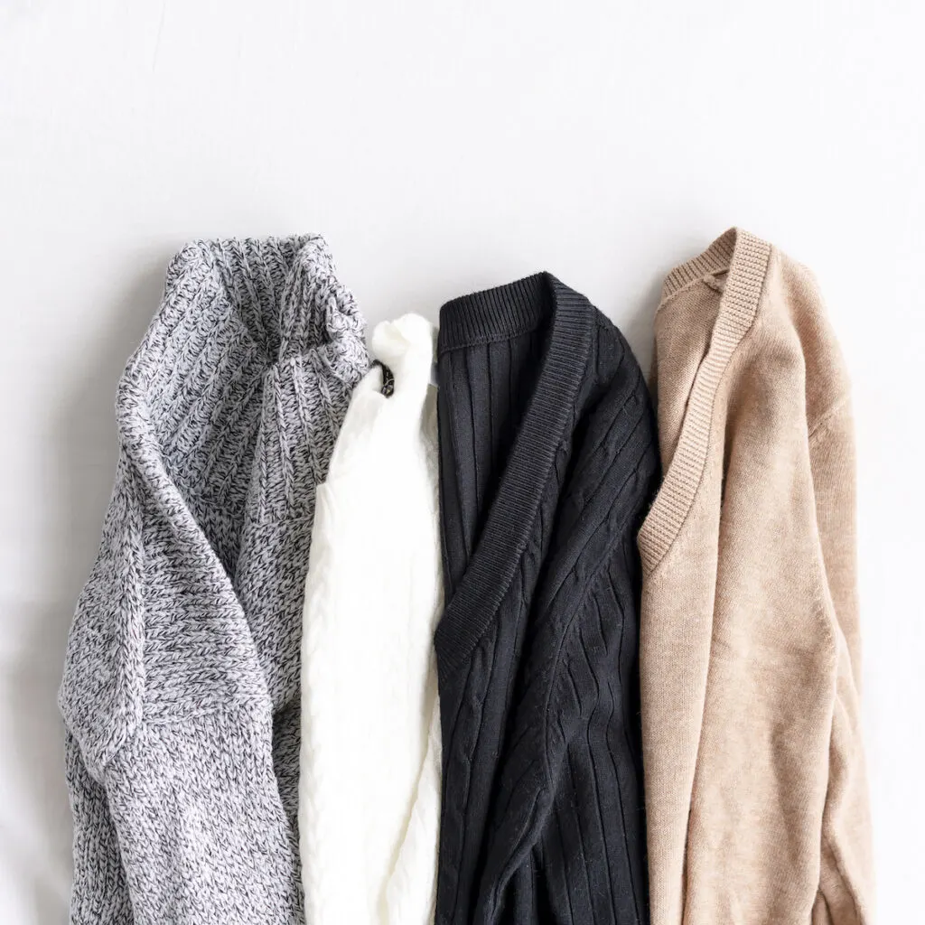 four sweaters on white background