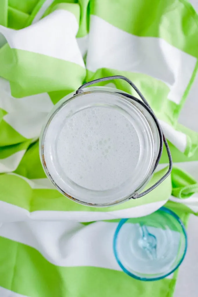 glass jar filled with homemade laundry detergent on green and white striped cloth